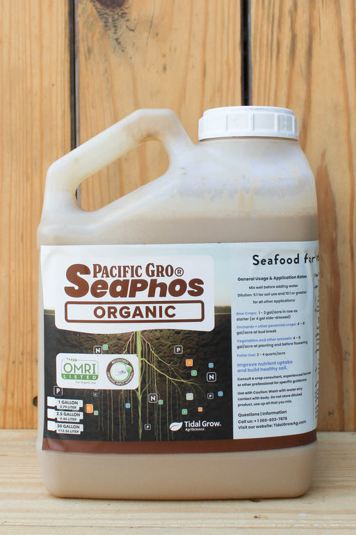 A plastic jug of Pacific Gro's SeaPhos Organic seafood fertilizer, filled with a light brown liquid, set against a rustic wooden plank background.