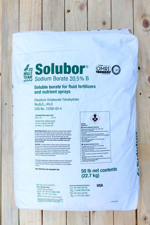 A 50 lb white bag of Solubor Sodium Borate 20.5% B for liquid fertilizer and nutrient spray, displayed flat against a light-colored wooden plank background.