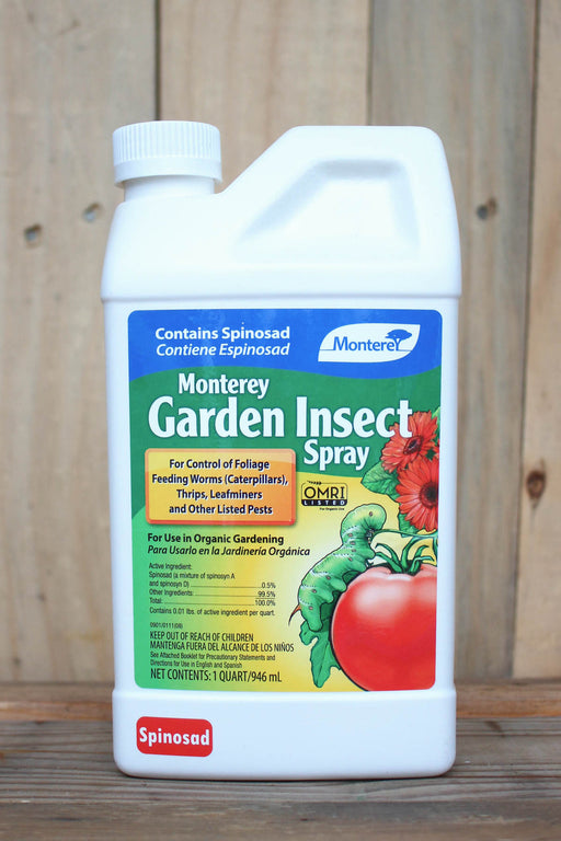A white plastic bottle of Monterey Garden Insect Spray with a colorful label, set against a rustic wooden plank background.