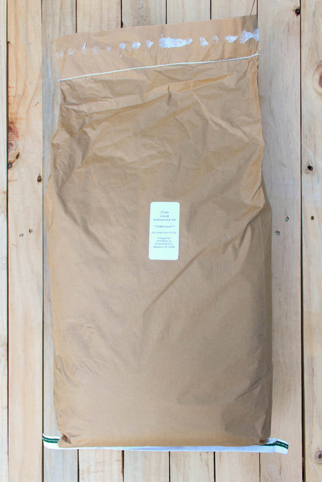 A large brown kraft paper bag with a white label in the center, placed flat on a light wood plank background.