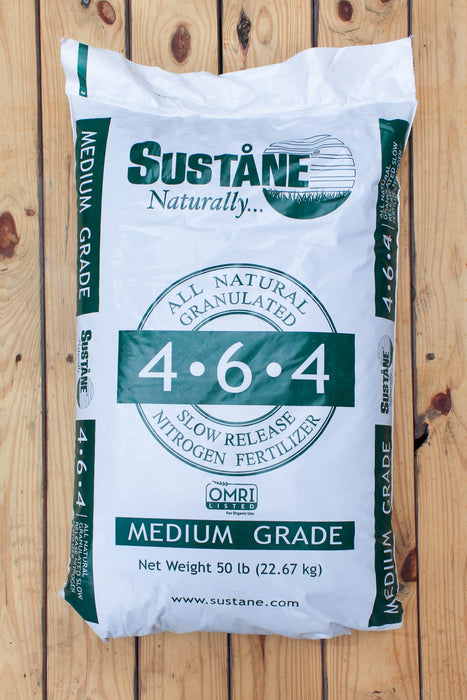 A 50 lb bag of Sustane Naturally 4-6-4 Medium Grade slow release nitrogen fertilizer, displayed on a light-colored wooden plank background.