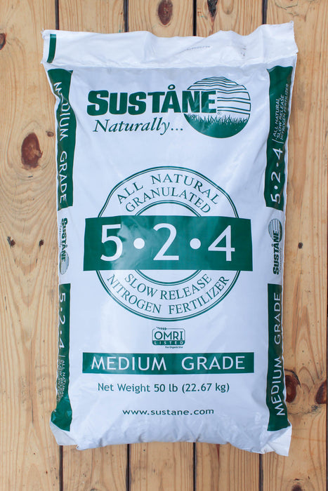 A 50 lb bag of Sustane 5-2-4 Medium Grade slow release nitrogen fertilizer, shown on a light-colored wooden plank background.