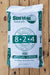 A 50 lb bag of Sustane 8-2-4 Medium Grade slow release nitrogen fertilizer, shown flat on a light brown wooden plank background.