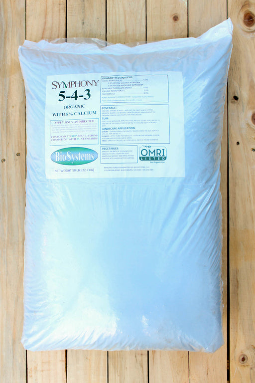 A large white plastic bag of Symphony 5-4-3 Organic, placed on a light-colored wooden plank surface. 