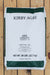 A 50 lb bag of Kirby Agri 46-50-00 Urea Granules, laid flat on a light-colored wooden plank surface. The bag is white with dark green bands at the top and bottom, and black text detailing the product name, ingredients, and net weight.