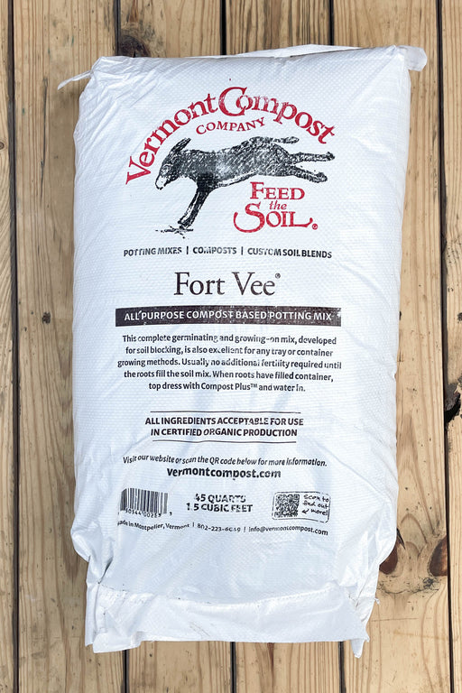 A white bag of Vermont Compost Company Fort Vee All Purpose Compost Based Potting Mix, displayed flat on a rustic wooden plank background.