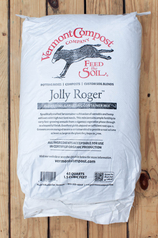 A large white bag of Vermont Compost Company Jolly Roger compost blend, displayed flat on a rustic wooden plank background.