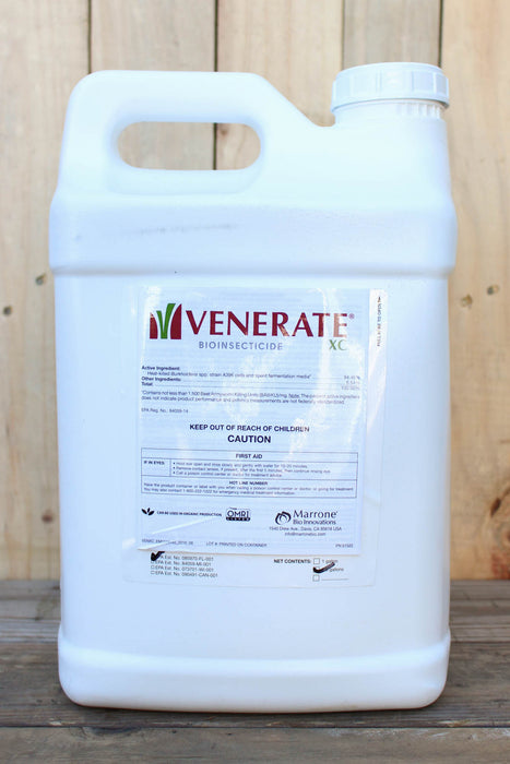 A large white plastic jug of Venerate Bioinsecticide standing against a light wood plank background.
