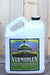 A large white plastic jug of Vermaplex with a colorful label featuring a tree, set against a rustic wooden background.
