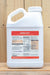 A white plastic jug of Weed Zap herbicide with a detailed product label, set against a rustic wooden plank background.