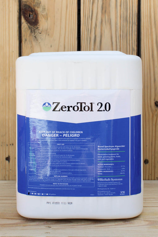 A large white plastic jug of ZeroTol 2.0 with a blue and white label, set against a rustic wooden plank background.
