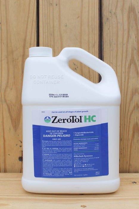 A white plastic jug of ZeroTol HC with a blue and white label, set against a light wood panel background.