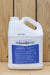 A white plastic jug of ZeroTol HC with a blue and white label, set against a light wood panel background.