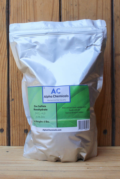 A 5 lb bag of Alpha Chemicals Zinc Sulfate Monohydrate standing upright against a wooden plank background.