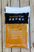 A bag of NutraSoft OP WP fertilizer, displayed on a light-colored wooden plank surface. The packaging features a black top section with white and orange branding, and a large orange lower section with white text.